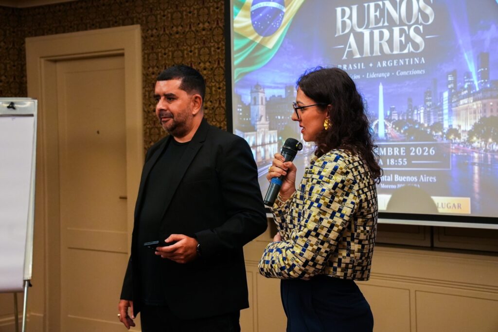 Mestre de cerimônias e apresentadora no palco em frente ao telão no Brazilian Summit Day — Turnê Buenos Aires 2026